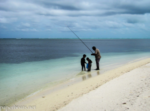 Father and sons fish at a beach in Maafushi